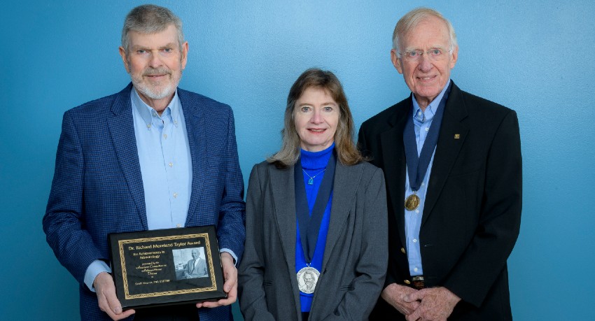 Three tropical medicine award winners display their plaques and medals.