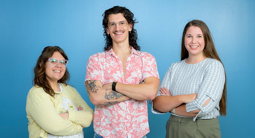 Three students in colorful casual clothing pose with their arms crossed.