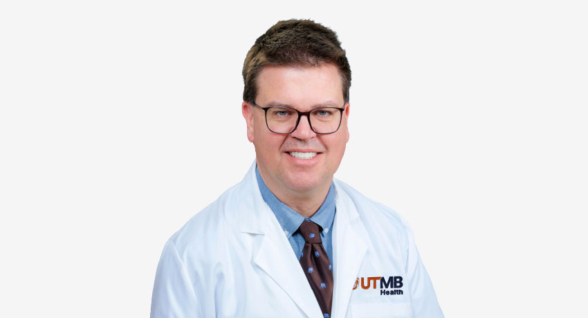 Max Wintermark appears in this headshot wearing a white coat feature an orange and blue UTMB logo.